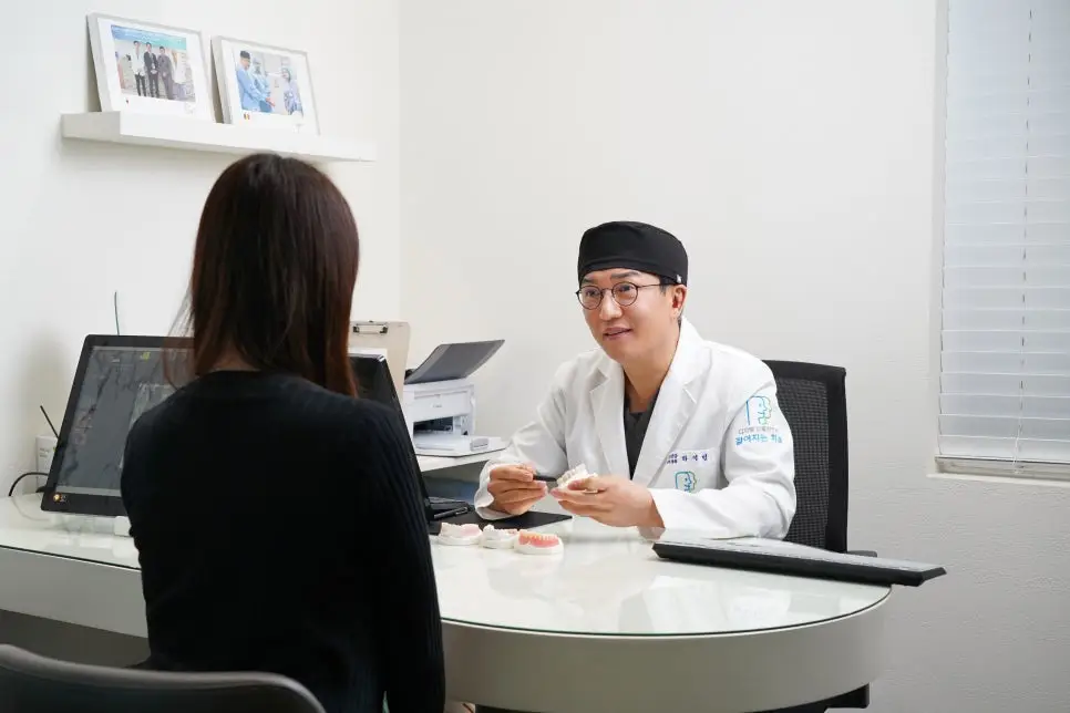강남역 젊어지는치과 원장이 환자와 마주 앉아 3D 디지털 모델을 활용해 임플란트 치료 계획을 친절하게 설명하는 상담실 전경